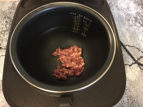 待內膽有熱時,倒適量的香油,放入肉末拌炒