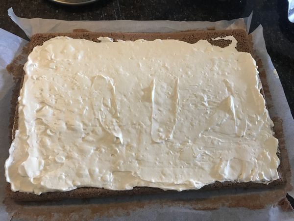在蛋糕開始捲起處用刀切2-3條不切到底的線條 (預防在捲蛋糕的時候裂開),均勻抹上備好的內餡-奶油乳酪鮮奶油,留一點邊預防餡料擠露出來