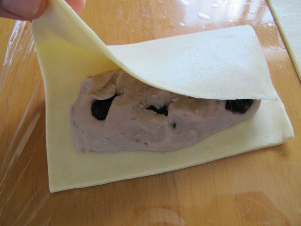 在起酥皮一邊放入五十克的芋頭餡, , 放入適量的葡萄乾,將起酥皮對折.