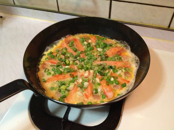 均勻鋪上蝦仁、鱘味棒、豌豆、蔥末、蒜末，加蓋悶煮。