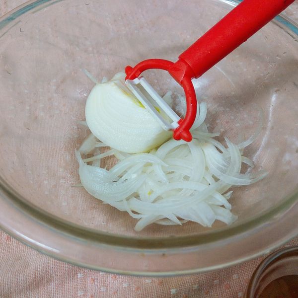 將洋蔥對切,剝除外皮和中心點的綠心後清洗乾淨.用刨絲刀將洋蔥刨成細絲狀.