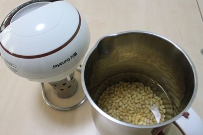 將黃豆洗淨浸泡冷水30分鐘後，倒掉浸泡水放置九陽豆漿機，再加入水，蓋上上蓋啟動機器按〔乾豆/濕豆〕，等候煮豆漿。