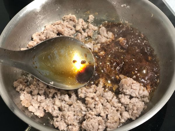 取100g絞肉炒至轉白後，自鍋邊加入醬油炒香後，加入米酒與絞肉炒均勻。