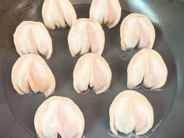 將鍋子噴上少量油，倒一些用塗抹的也可以。

將水餃放入。

（盡量找獨立裝的水餃，較容易立起）
（盡量使用不沾鍋為佳）

倒入一碗水，可以多一些也沒關係。

轉中大火，蓋上鍋蓋，計時⌛️6分鐘即可。