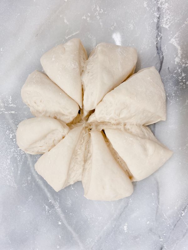 把發酵好的麵糰拿出來放在桌上，不要揉它，直接切成「米」字型，分成8份(每份約55~60克)；

註1：可以灑一點手粉防止沾粘。
註2：由中心點向外的分切法，稍後比較容易擀開成三角的烤餅形狀。