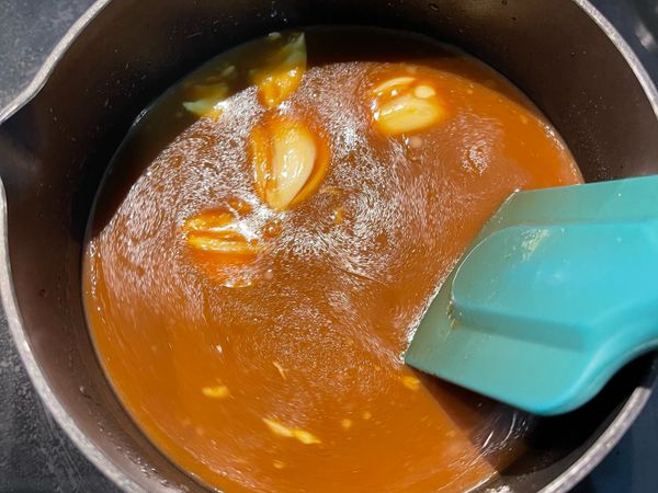 蒜頭拍扁去皮後放入鍋中，並加入水拌勻，以小火邊攪拌邊煮；