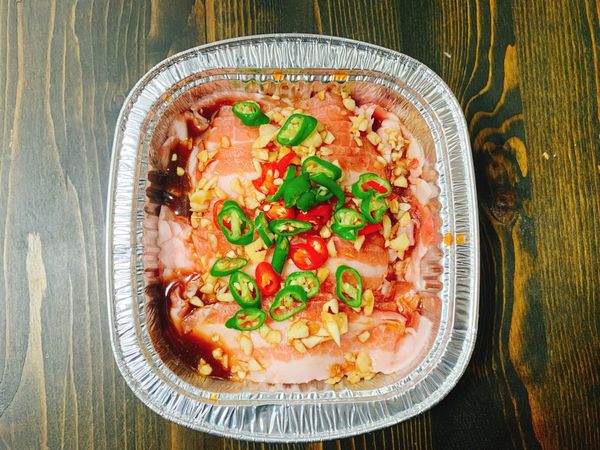 再均勻鋪上五花肉片，淋上醬汁，撒上辣椒末，蓋上鋁箔紙