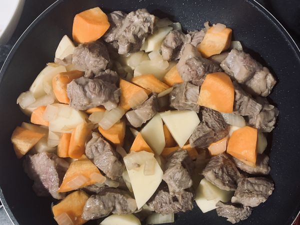 依次加入牛肉、紅蘿蔔、馬鈴薯，將食材們均勻炒香
