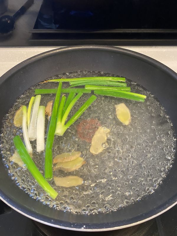 燒一鍋煮滾的水，倒入米酒、蔥段、薑片。