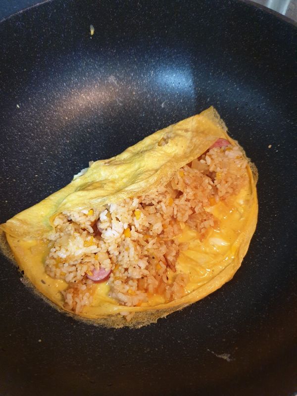 將蛋皮捲起，蓋上盤子，再將蛋包飯倒扣至盤中，淋上番茄醬