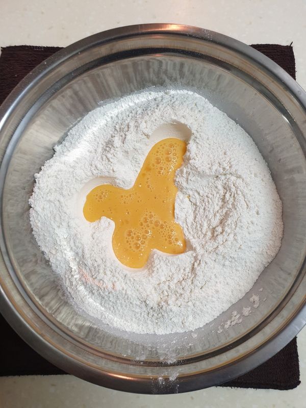 麵粉挖個洞，倒入打勻的蛋液並輕輕翻拌