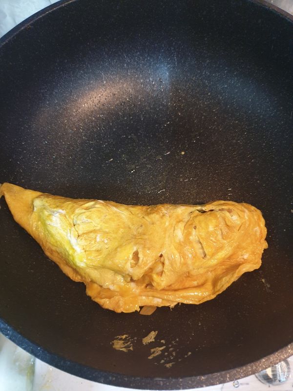 將蛋皮捲起，蓋上盤子，再將蛋包飯倒扣至盤中，淋上番茄醬