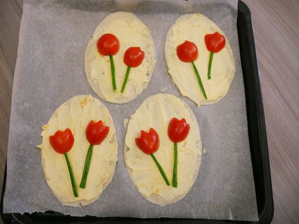 抹上乳酪起士醬、擺上切成花型的小番茄及根狀的小黃瓜，以預熱180度烤箱烤約10分鐘、最後擺上生菜點綴葉子。