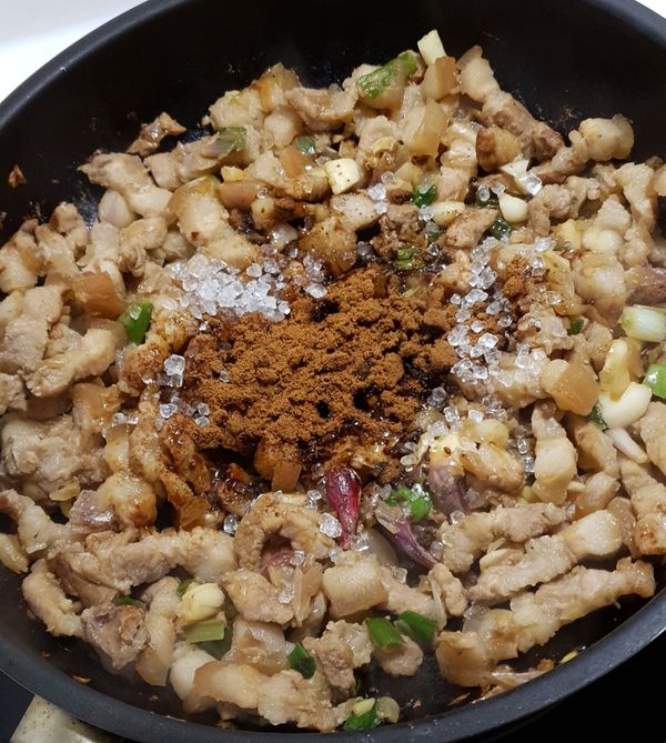 將肉炒至翻白後，再加入黑糖及冰糖，繼續翻炒。