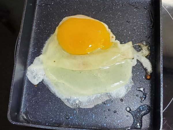 在鍋中加入油，將蛋打入。