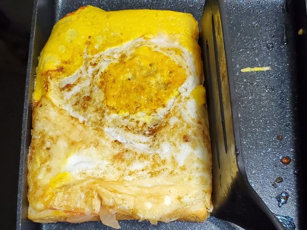 將吐司往其中一邊的角落貼合，使其邊角的蛋液能貼住吐司邊。