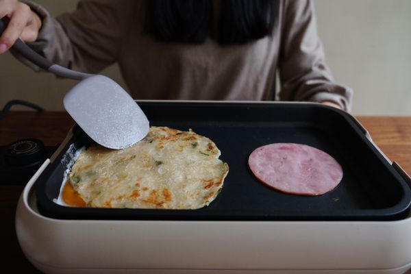 將餅皮放上半熟蛋後，下火腿片煎熟