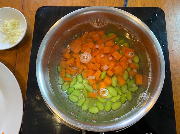 準備一鍋滾水，將毛豆及紅蘿蔔丁煮熟