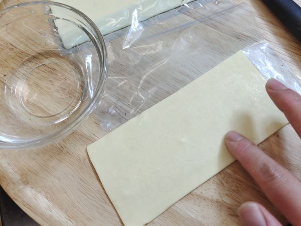 將市售的方形酥皮打開、對切一半。那因為今天只做示範一種口味所以是對切長方形、那如果做不同種類可以斜切成三角形、就包成三角形、甚至包成自己喜歡的形狀都可以、這樣做完才知道不同的口味是什麼外型
