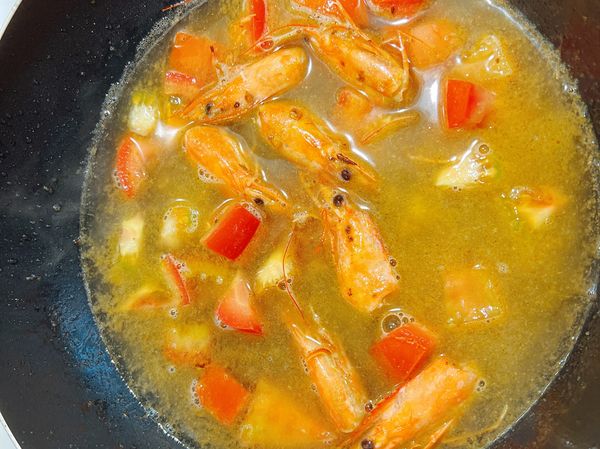加入蕃茄拌炒後，加入一碗半的水，煮至滾後將蝦頭取出