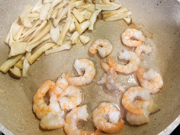 再將杏鮑菇推到一邊，再下蝦仁炒至變色後撈出備用，避免蝦子太熟。