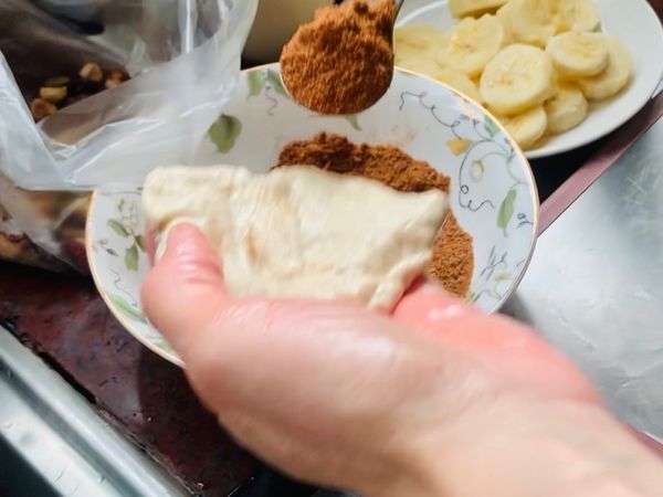 手摸些油將發酵好的麵糰取出適當的大小依序包入拌入肉桂粉的黑糖、堅果、香蕉後包起來。封口處務必包密合否則煎時內餡會流出來。