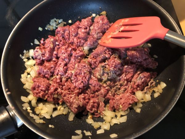 在鍋裡加入1大匙的油，等油熱了後加入牛絞肉，慢慢的煮到乾掉後加入蒜碎略炒(也可以加入一些洋蔥碎)