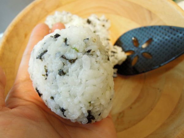 取ㄧ糰飯，第一次先捏緊。第二次再塑形呈三角飯糰，或你喜歡的樣式。