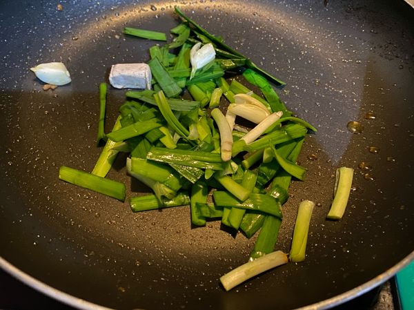開火，油、蒜頭、韭菜、雞湯塊丟進去爆香