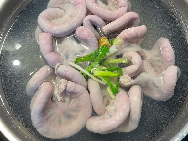 水滾後放米酒，再下粉腸；粉腸上白白的部份是筋膜和脂肪，漢子不會先剪掉，因為ㄧ起水煮會讓粉腸更香；