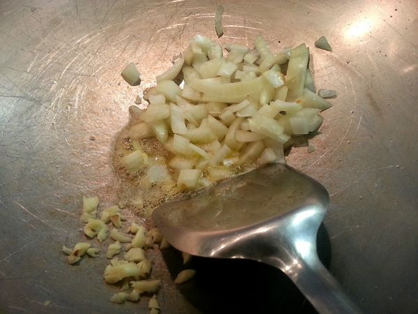 鑊中下牛油燒熱，下蒜粒和洋蔥炒至香。