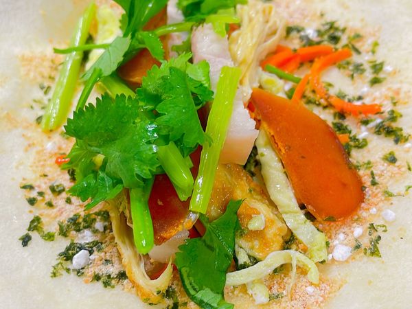 將烏魚子浸泡米酒三分鐘，
熱鍋烤一下，
放涼之後⋯切斜片備用！
各類蔬菜洗淨後，
切成絲狀👇
用橄欖油清炒盛盤！
不需要加調味料！
潤餅皮一張一張對折放在盤子
海苔酥、花生糖粉～
可以攪拌在一起備用！
2張潤餅皮打開，灑上步驟4
再將各類蔬菜絲放上來、
最後放烏魚子、香菜，再將潤餅捲起來包好！