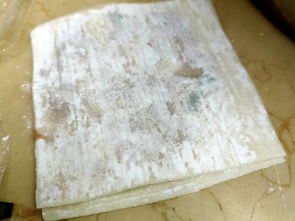 準備兩片皮（這才是剩下餛飩皮）將內餡加入一小匙（約咖啡攪拌匙一匙），壓扁放置一旁