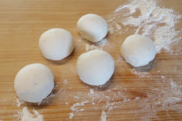 將發酵好的麵糰取出，壓平，分割，揉成每個約150g的麵糰。覆蓋後醒20分鐘。