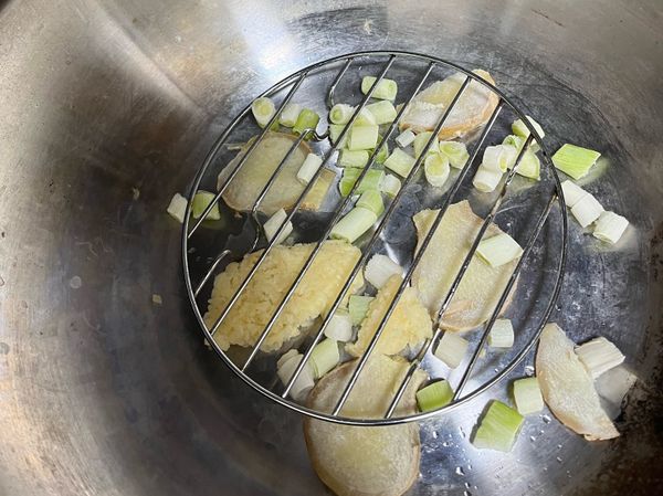 薑蔥薑蒜放入鍋中，放上蒸架加入一碗水或米酒