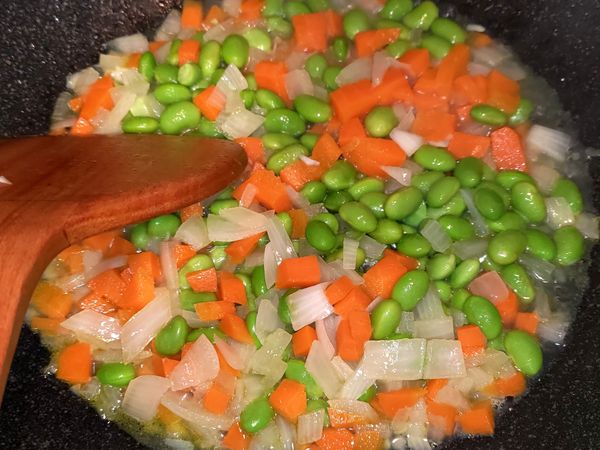 毛豆放入，若是冷凍毛豆仁，事先要用冷水洗2-3次，幫助解凍
加入少量的水（只要到食材的底部範圍就可以），過程盡量把料往中間集中，讓下層接觸到水，翻動2-3次即可，翻完再往中間集中，讓蔬菜都炒熟