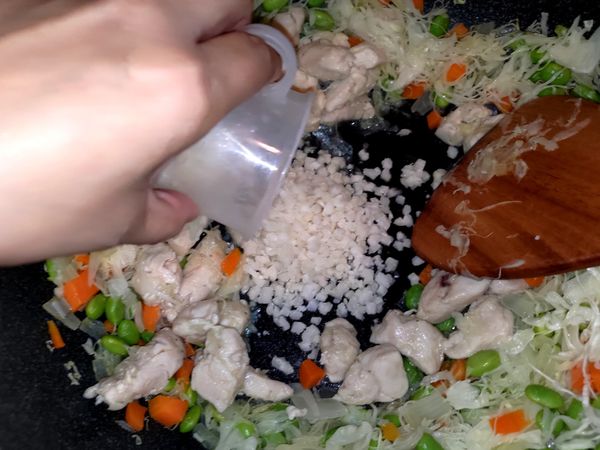 雞肉也往旁邊撥開，倒入花椰米，用一樣的方式炒到花椰米變軟，熟透