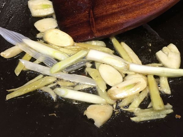 辛香料香氣釋出後加入蔥白段拌炒。