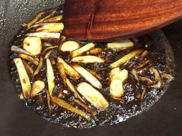 蔥香釋出後醬油沿著鍋邊、靠近辛香料繞一圈加入，醬油經過熱鍋嗆過後的味道會有股焦香味，吃起來味道更香濃、不死鹹，接著加入水、米酒及砂糖拌炒均勻。