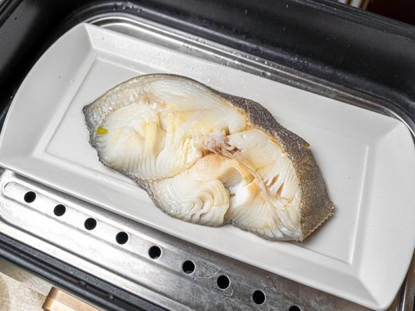 鱈魚蒸熟後，將薑、蔥夾起來並倒掉湯汁。