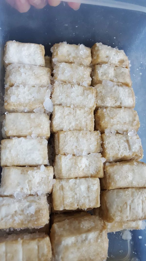 把毛豆腐放在盒子裡面灑上鹽巴高梁讓毛豆腐出水，變得紮實，時間大概三天如果天氣太熱可以放個陰涼的地方