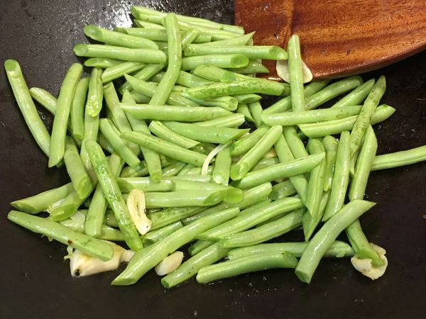 蒜頭香氣釋出後加入四季豆段拌炒。
加入少許水幫助四季豆炒至變透明、炒熟。