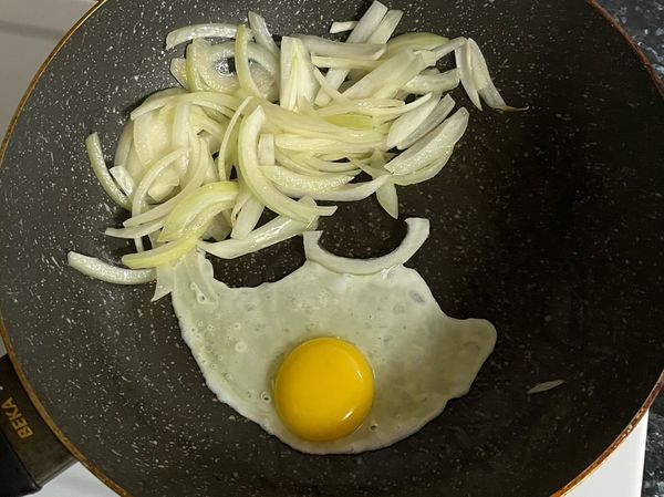 將洋蔥撥至鍋邊，下雞蛋。依荷包蛋煎法，大約蛋半熟後，移到洋蔥區。