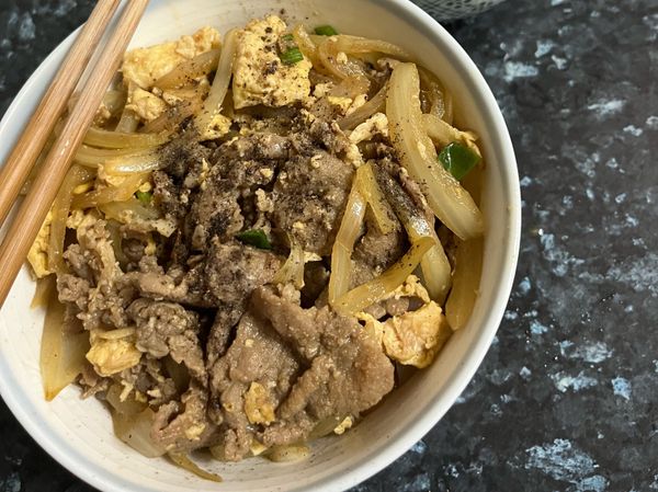 先將湯汁淋一些在飯上，將料蓋在飯上。撒些胡椒粉，或是七味粉。