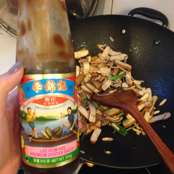 隨之加入豆乾拌炒後，加入蠔油一起繼續辦炒，接著在鍋邊嗆一些醬油，撒上蔥綠再伴一下
