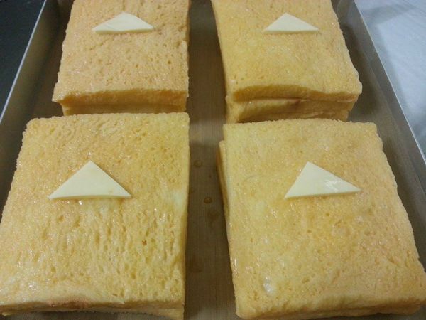 取一容器將雞蛋打散,找個有深度的盤子將雞蛋倒入,把三層土司每一面都沾上蛋液,(包括邊邊部份),放在烤盤上...