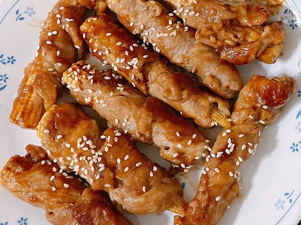 將梅花豬肉片纏繞在玉米捲上，在接縫處沾一點玉米粉。
［醬料］：醬油、米酒、糖，可依個人喜好自由調配。
在平地鍋上倒少許的油，將玉米筍肉捲放下去煎，8分熟後倒醬汁，直至全熟。最後收汁灑上白芝麻即完成。