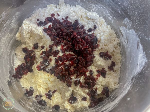 還能看到一點麵粉時，加入切碎的蔓越莓乾，
用橡皮刮刀混合後改用手抓成團。