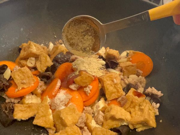 3、再放入木耳、紅蘿蔔、油豆腐翻炒均勻，再加所有調味料翻炒後，加水沒過食材