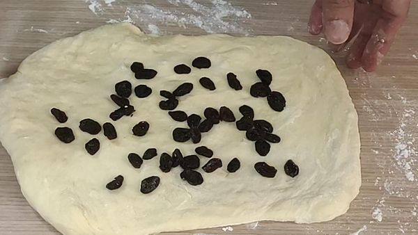 把麵團壓成長方形，加入葡萄乾